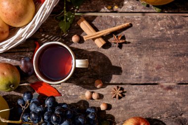Cozy autumn rustic still life: cup of tea, fruits, vegetables, hazelnuts and cinnamon sticks. Autumn aesthetic coziness. Thanksgiving Day concept with place for text