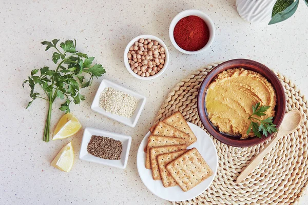 Healthy vegetarian appetizer. Traditional hummus with grain cookies, parsley, lemon slices. Parsley, paprika, roman cumin seeds, chickpeas, sesame ingredients.