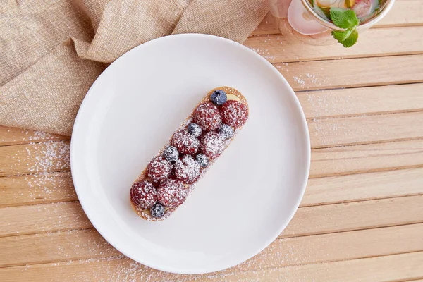 French blueberry and raspberry tart on white ceramic plate. Top view food. Aesthetic food.