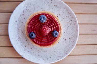 Beyaz seramik tabakta Fransız yaban mersini ve ahududu turtası. Estetik kahvaltı. En iyi yemek..