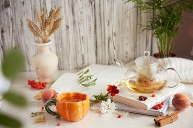 Kitaplarda çaydanlıkta doğal organik ıhlamur çayı ve balkabağı şeklinde bir fincan çay. Kuru kokulu çiçekler, buğday, sonbahar düzenlemeleri, incirler, şeftaliler. Rahat atmosperic evde dinleniyor