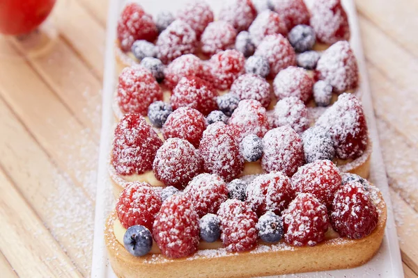 French blueberry and raspberry tartlets sprinkled with powder close up. Top view food. Aesthetic food.