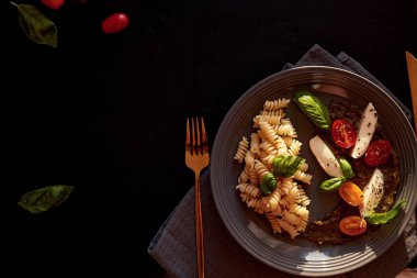 Domatesli Caprese salatası, soslu mozzarella ve fesleğen. İtalyan usulü makarna. Siyah kırsal arkaplanda boşluk kopyala.