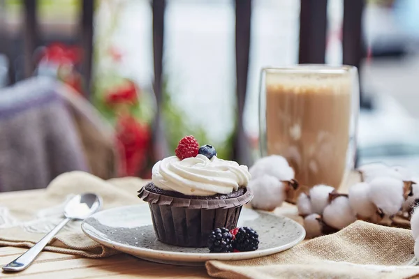 French gluten and sugar free raspberry and blueberry cupcake and cup of latte. Cozy autumn breakfast at the terrace