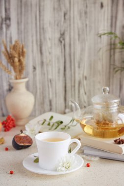 Çaydanlıkta ıhlamur çayı ve bir fincan çay. Kuru kokulu çiçekler, sonbahar düzenlemeleri ve kitap. Sıcak atmosperic evi. Boşluğu kopyala.