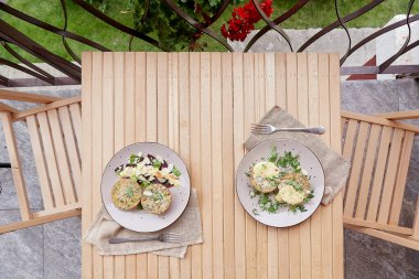 Tofulu vejetaryen kekler, bezelye filizi, otlar, badem gevreği ve sebzeler ahşap masada. Terasta sağlıklı bir kahvaltı..