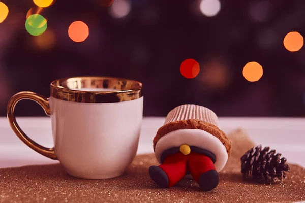 Cozy Christmas tea time. Decorative cupcakes and a cup of tea in front of the Christmas tree. Good mood, festive mood. Selective focus