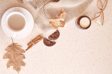 Pastel feminen sonbahar arkaplanı - gündelik kadın süveteri, tarçın çubukları, mum, sonbahar yaprakları arasında gladyatörlük. Estetik kahve zamanı. Boşluğu kopyala.