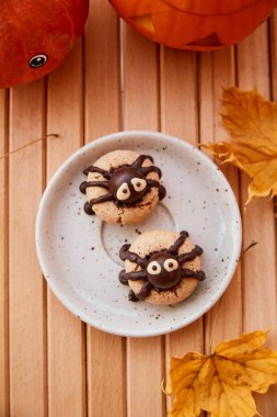 Sonbahar yaprakları arasında Cadılar Bayramı balkabaklı şirin örümcekler kurabiyeleri. Şeker mi şaka mı? El yapımı kurabiyeler.