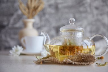 Çaydanlıkta bitkisel ıhlamur çayı ve bir fincan çay. Çay saati dinleniyor. Çevre dostu sürdürülebilir yaşam tarzı. Buğday, kasımpatı, sonbahar süslemeleri ve defter. Sıcak atmosferik ev