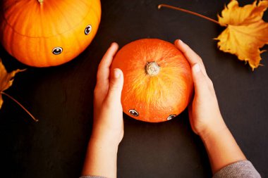 Çocuk komik bir balkabağı tutuyor, Cadılar Bayramı için balkabağı feneri. Tatil için el yapımı dekorasyonlar. Çocukların yaratıcılığı.