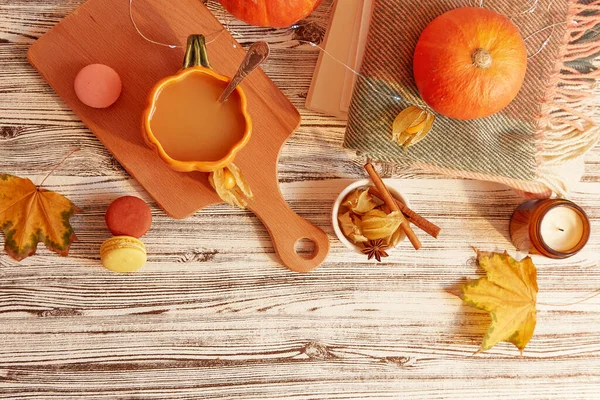 Seasonal pumpkin latte in shape of pumpkin cup among desserts and leaves, Lagom, cozy home.