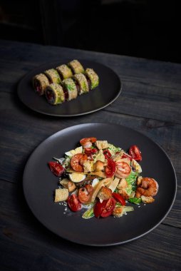 Sade yeşil arka planda Japon mutfağı suşisi. Sezar salatası ve arka planda sağlam bir makarna için karides fotoğrafı.