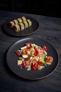 Sade yeşil arka planda Japon mutfağı suşisi. Sezar salatası ve arka planda sağlam bir makarna için karides fotoğrafı.