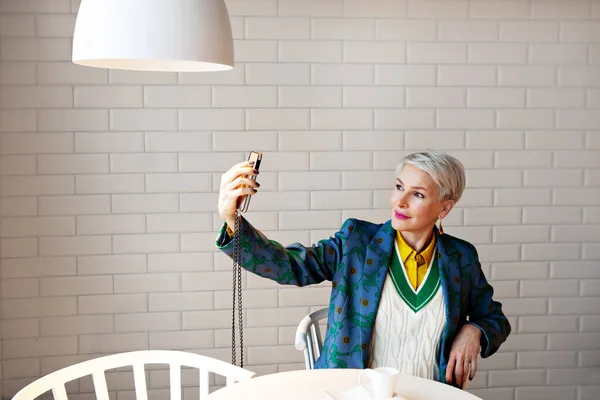 Starší Krátká Šedé Vlasy Žena Drží Smartphone Přičemž Selfie Sedí Stock Fotografie