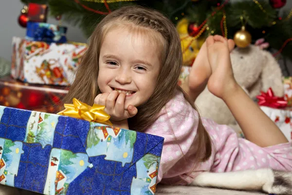 Het meisje met een geschenk onder de kerstboom — Stockfoto