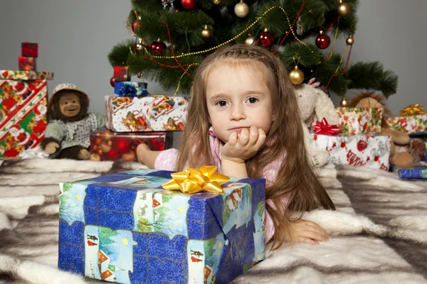 Het meisje met een geschenk onder de kerstboom — Stockfoto