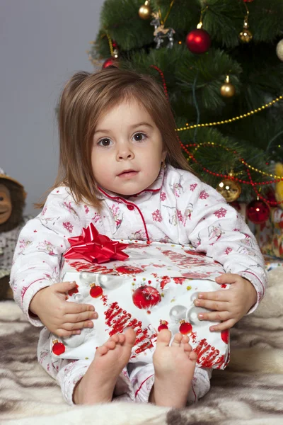 La ragazza con un regalo sotto l'albero di Natale — Foto Stock