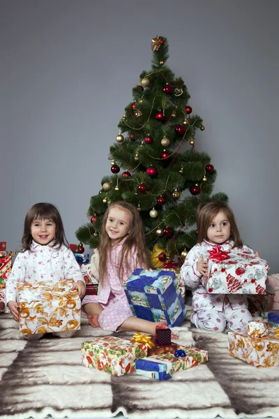Τρία κορίτσια, κάτω από το χριστουγεννιάτικο δέντρο με δώρα — Φωτογραφία Αρχείου