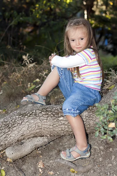 Happy young girl sitting near a tree in the garden — Stock Photo, Image