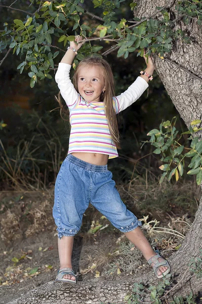 Chica joven y feliz de pie cerca de un árbol en el jardín —  Fotos de Stock