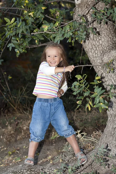 Chica joven y feliz de pie cerca de un árbol en el jardín —  Fotos de Stock