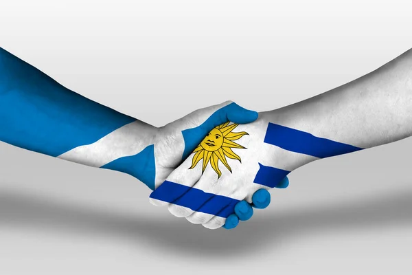 Рукопожатие Между Уругваем Шотландскими Флагами Раскрашенными Руках Иллюстрация Вырезкой — стоковое фото