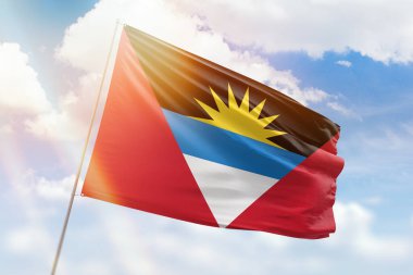 Güneşli mavi gökyüzü ve antigua barbuda bayrağıyla bayrak direği