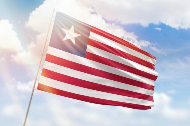 Güneşli mavi gökyüzü ve Liberya bayrağıyla bayrak direği