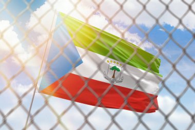 A steel mesh against the background of a blue sky and a flagpole with the flag of equatorial guinea