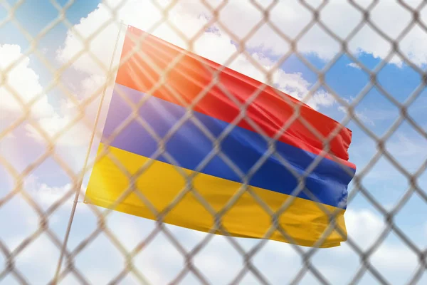 A steel mesh against the background of a blue sky and a flagpole with the flag of armenia