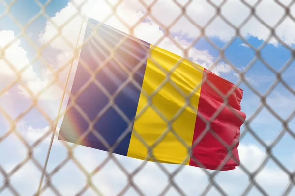A steel mesh against the background of a blue sky and a flagpole with the flag of chad