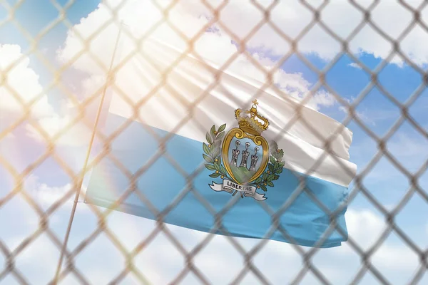 A steel mesh against the background of a blue sky and a flagpole with the flag of san marino