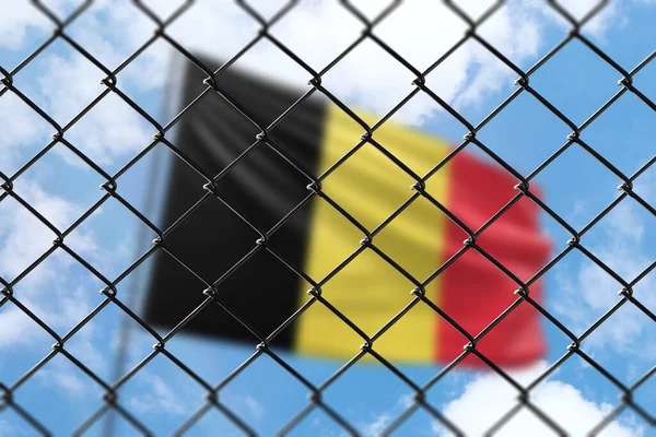 A steel mesh against the background of a blue sky and a flagpole with the flag of belgium