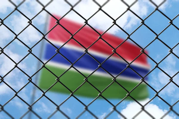 A steel mesh against the background of a blue sky and a flagpole with the flag of gambia