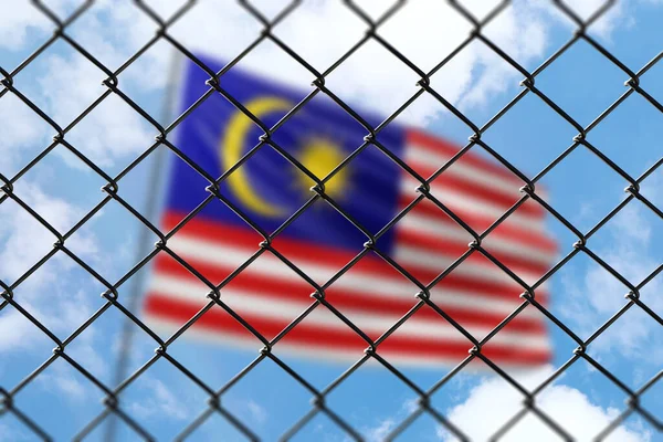 A steel mesh against the background of a blue sky and a flagpole with the flag of malaysia