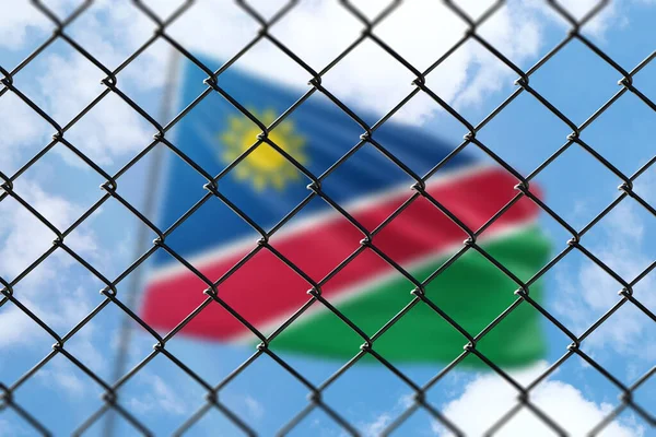 A steel mesh against the background of a blue sky and a flagpole with the flag of namibia