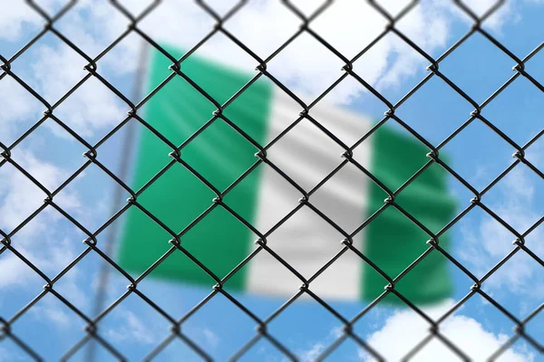 A steel mesh against the background of a blue sky and a flagpole with the flag of nigeria