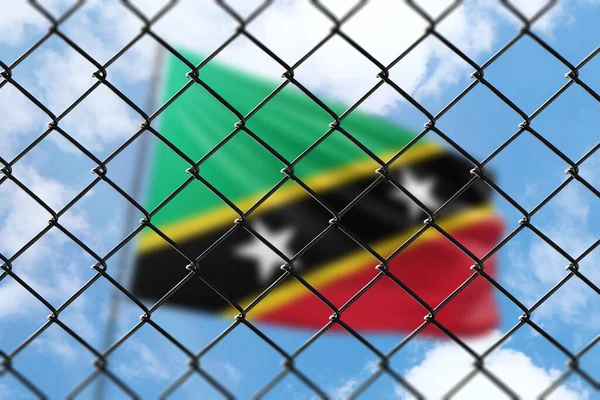 A steel mesh against the background of a blue sky and a flagpole with the flag of saint kitts and nevis