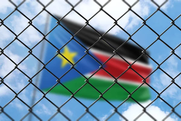 A steel mesh against the background of a blue sky and a flagpole with the flag of south sudan