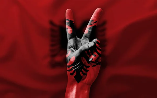 Abania bayrağıyla zafer işareti yapıyor.