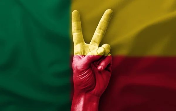 Hand making the V victory sign with flag of benin