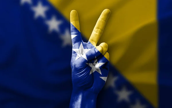 Hand making the V victory sign with flag of bosnia