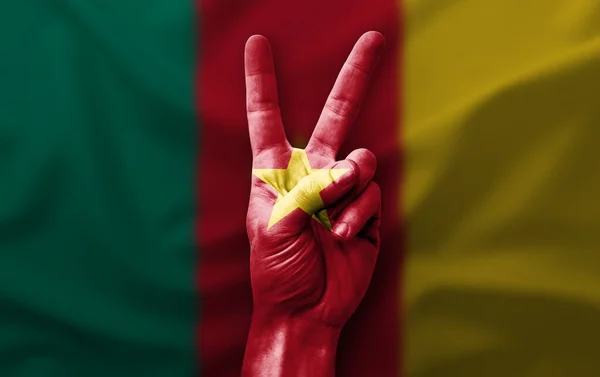 Hand making the V victory sign with flag of cameroon