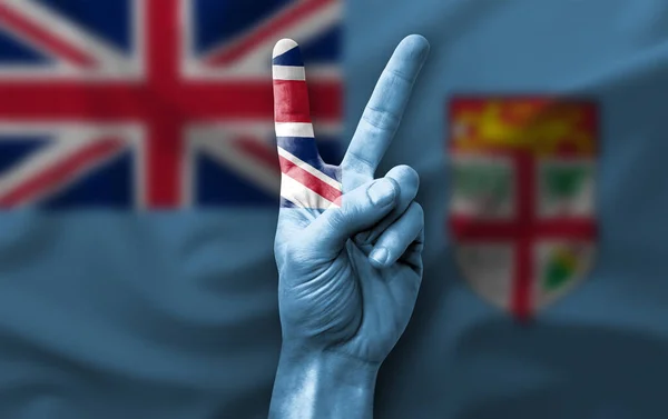 Hand making the V victory sign with flag of fiji