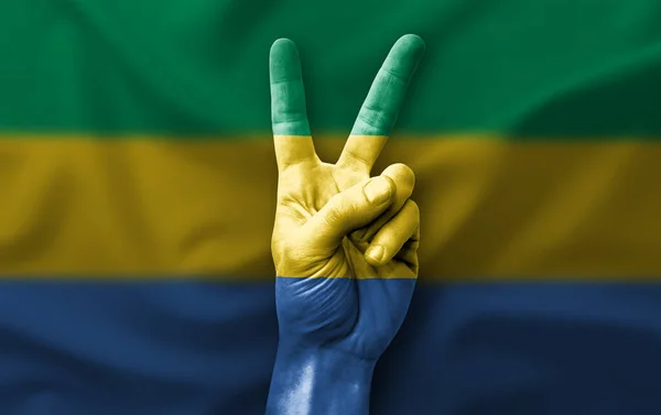 Hand making the V victory sign with flag of gabon