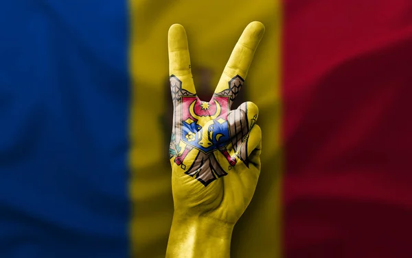 Hand making the V victory sign with flag of moldova