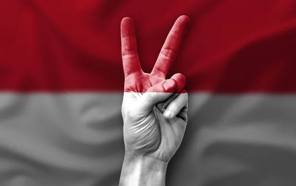 Hand making the V victory sign with flag of monaco