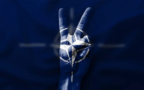 Hand making the V victory sign with flag of nato