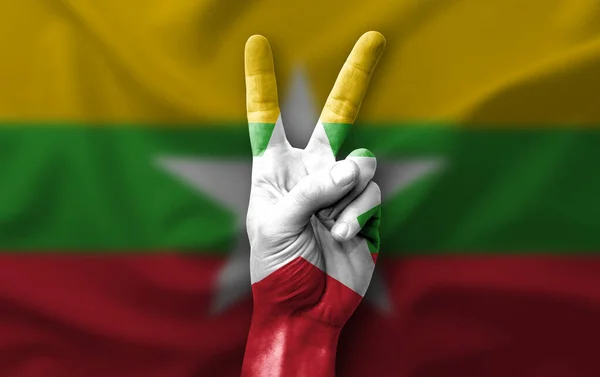 Hand making the V victory sign with flag of myanmar